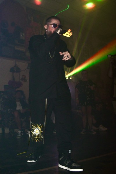 Performer on stage singing under bright green and red lighting